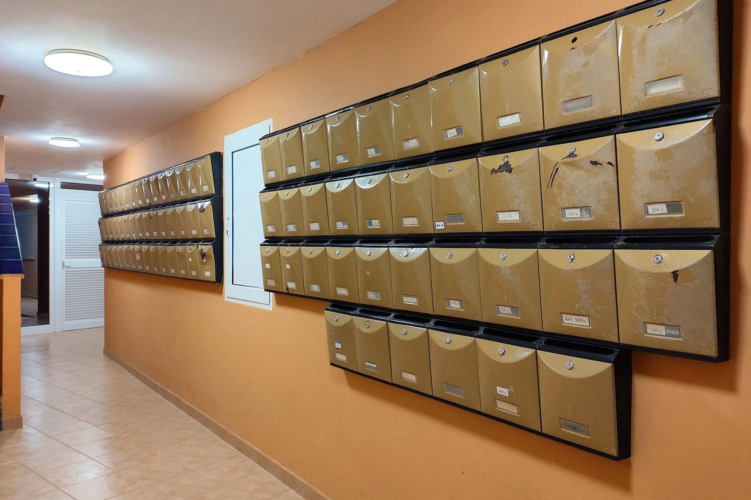 Rows of numbered metal letterboxes, one labelled Apt 105A, in an apartment hallway