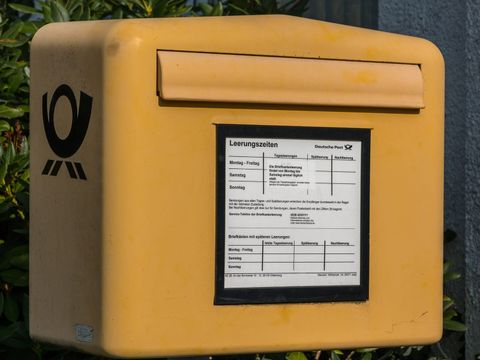 Yellow Deutsche Post letterbox with a collection times sign on the island of Juist
