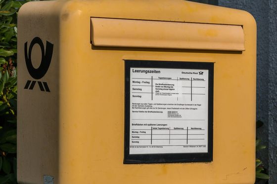 Yellow Deutsche Post letterbox with a collection times sign on the island of Juist