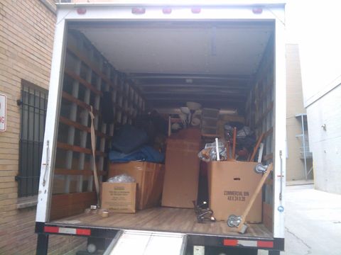 Open moving truck loaded with cardboard boxes, a lamp and furniture