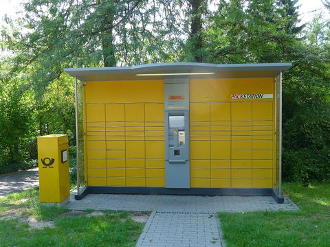Yellow DHL Packstation parcel locker next to a post box among trees in Heidelberg