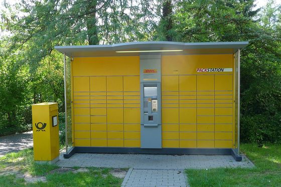 Yellow DHL Packstation parcel locker next to a post box among trees in Heidelberg