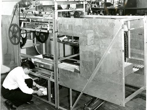 Historic prototype letter sorting machine for the US Post Office with an engineer loading mail