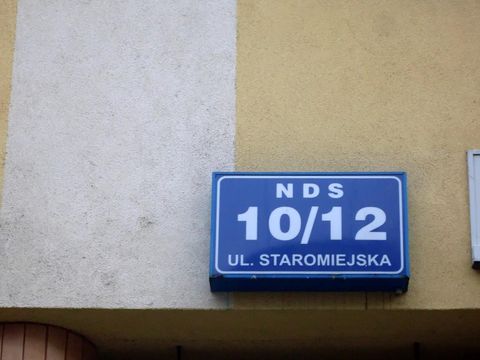 Blue house sign reading NDS 10/12 ul. Staromiejska on a yellow wall in Gdynia