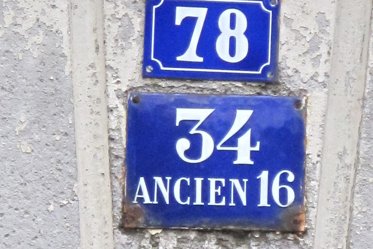 Blue enamel plates showing house numbers 78 and 34, old number 16, on one wall